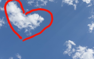 Bild zeigt einen leicht bewölkten Himmel, auf dem der Umriss einer Wolke mit einer Herzform umkreist wurde.
